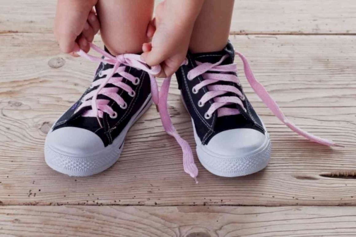 Niña autónoma atándose los cordones