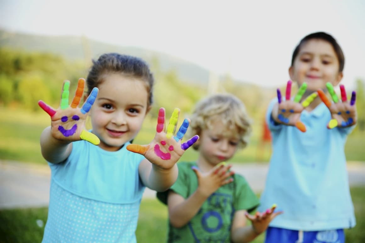 Niños con las manos pintadas jugando a juegos de aprendizaje cooperativo